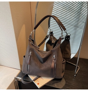 Détail du sac hobo en daim marron foncé avec fermetures éclair et texture de matière douce