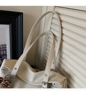 Detail of comfortable pebble leather handle with silver hardware on a cream tote bag