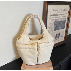Detailed macro view of cream quilted bucket bag with large dual front pockets