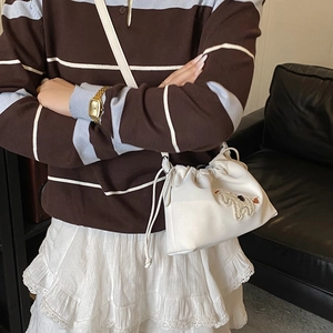 Close-up of white drawstring bucket bag with cute plush animal patch and long shoulder strap
