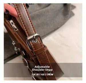Detail of adjustable leather shoulder strap with silver buckle on brown crossbody bag
