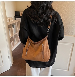 Détail d'un sac hobo marron en suédine avec fermetures éclair en métal et bandoulière réglable