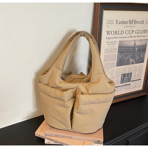 Close-up of khaki quilted bucket bag with dual front pockets and soft padded texture