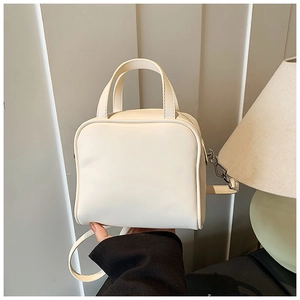 Close-up of cream PU leather square handbag with silver hardware and adjustable strap