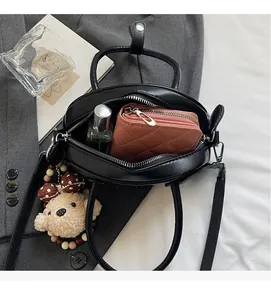 Top view of black leather bowling bag showing spacious interior with wallet and perfume
