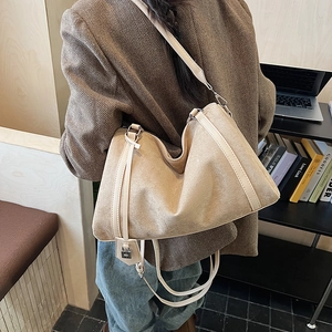 Dettaglio di una grande borsa hobo in camoscio beige con tracolla in pelle in ufficio