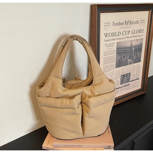 Detailed close-up of a beige quilted tote bag with front pockets on vintage book decor