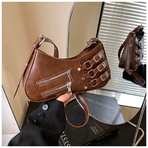 Detail view of a vintage brown crescent bag featuring metal zippers and buckle hardware
