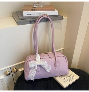 Detail of lavender Boston bag with golden Maven & Chic logo and white lace bow