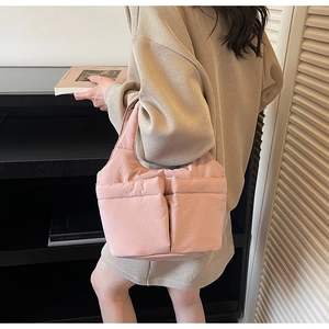Pale pink quilted tote bag with padded bubble texture shown in a lifestyle commuter setting