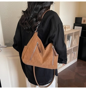 Détail du sac bandoulière en daim marron avec deux poches zippées et bandoulière en cuir