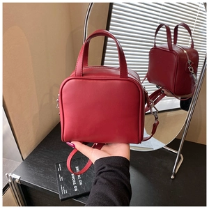 Close-up of the dark red leather handbag featuring dual handles and silver hardware details