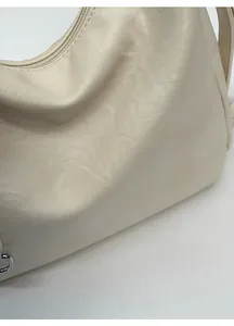 Close-up of the beige PU leather texture with fine grain and soft pleated details on the bag