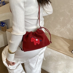 Detail of red drawstring bucket bag with horse embroidery on a white dress