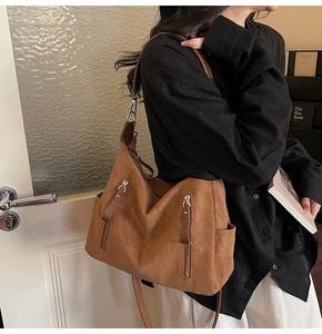 Gros plan sur un sac hobo en daim marron avec doubles fermetures éclair et bandoulière