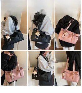 Detail of lychee pattern leather tote bag with metallic buckle and plush bear charm