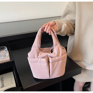 Detail of light pink quilted tote bag with multiple pockets held by a model in a room