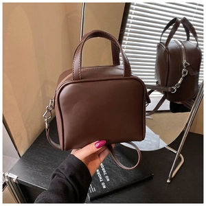 Close-up of deep brown leather textured handbag with dual ring handles and zipper