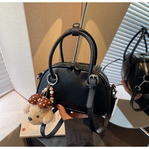 Detail of black leather bowling bag with silver hardware and plush dog charm