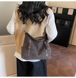 Détail du grand sac demi-lune marron vintage avec zips latéraux porté par un mannequin