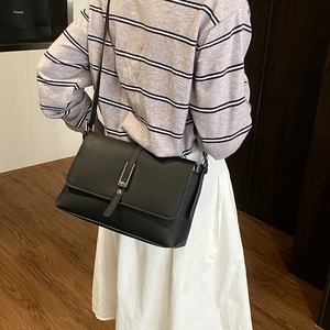 Modern black lychee leather crossbody bag shown on model with silver metal buckle details