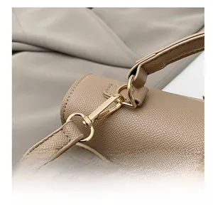 Detail of high-quality gold metal clasp on beige textured leather shoulder bag strap