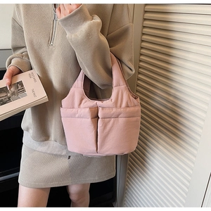 Detail of pink quilted bucket bag showing soft padded texture and large front pockets