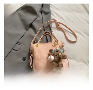 Detailed macro of pink quilted bucket bag with gold chain and plush bear charm