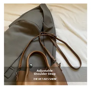 Detail view of brown lychee grain leather tote bag with an adjustable shoulder strap