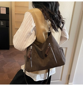Détail montrant la texture cuir mat marron foncé et les fermetures éclair de ce sac