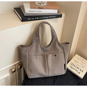 Detail of canvas tote bag showing two front pockets with metal snaps and sturdy handles