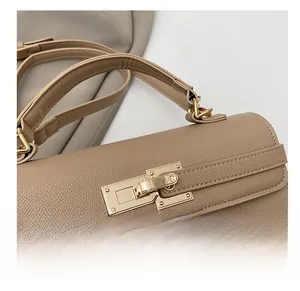 Close-up of golden rectangle twist lock and litchi grain texture on khaki leather bag