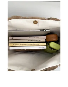 Macro shot showing large storage space of the brown plush tote bag with a laptop and books