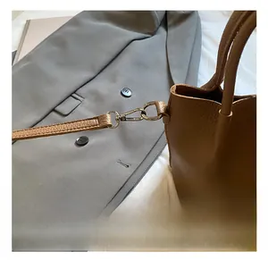 Detail of silver metal hook and brown lychee grain leather texture on the handbag strap