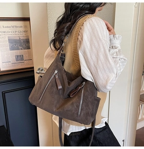 Détail du sac hobo en daim marron foncé avec doubles fermetures éclair argentées et texture