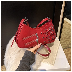 Close-up of red leather moon bag featuring silver zippers and punk buckle strap details
