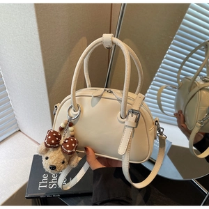 Detailed view of white bowling bag with soft teddy bear charm and silver hardware accents