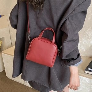 Deep red square leather mini handbag styled on a model wearing a grey blazer