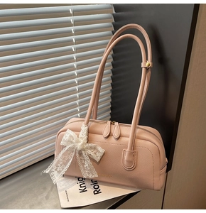 Detailed view of pink Boston bag featuring lychee grain leather and lace bow decoration