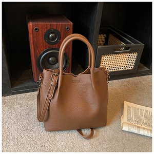 Detailed macro view of the brown lychee grain texture on a leather tote bag