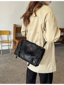 Retro black leather shoulder bag with large flap and straps on female model