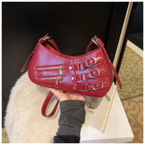 Detail of red punk shoulder bag with silver buckles and zippers on glossy leather