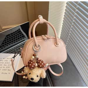 Close-up of pink Boston bag with smooth matte leather texture and cute plush puppy charm