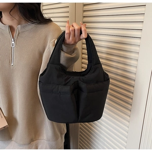 Detail of black quilted bucket bag with symmetrical deep pockets and padded texture