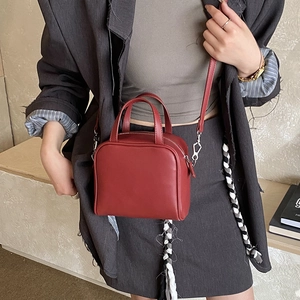 Deep red matte leather handbag with thin shoulder strap shown in a fashion model styling