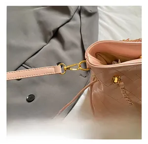 Detailed close-up of pink quilted crossbody bag with premium gold metal hook hardware