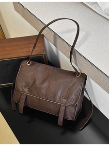 Retro deep brown leather shoulder bag with vintage texture and adjustable strap on dark surface