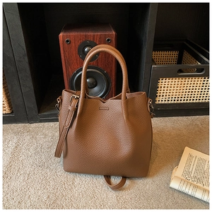 Detailed view of brown lychee grain leather bucket bag on soft carpet with vintage decor