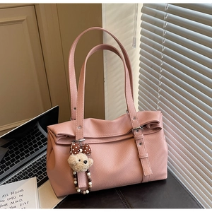 Detail of pink lychee texture bag featuring a plush bear charm and long thin handles