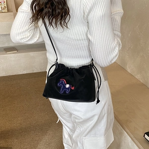 Detail of a black drawstring bucket bag featuring a colorful horse embroidery patch